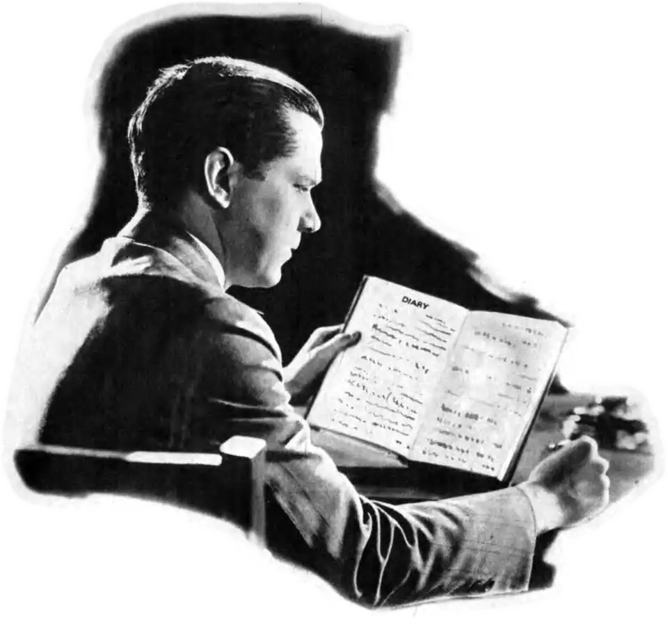 Black and white photo of a man in a suit reading at a desk