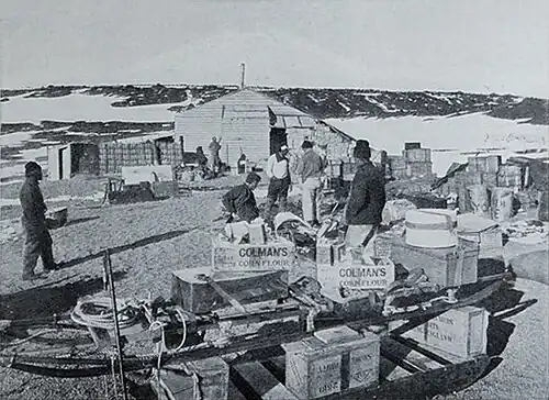 Photo of crates and other supplies arrayed neatly outside a wooden hut