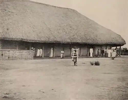A large building, with several pedestrians outside