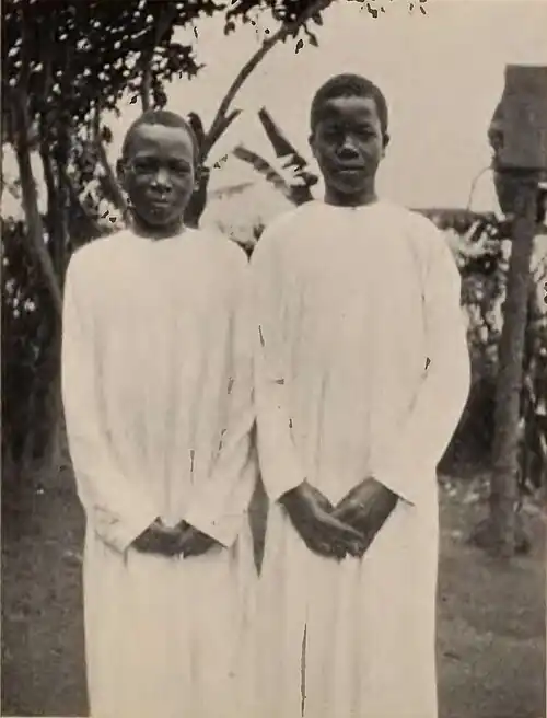 Two boys standing, wearing white robes
