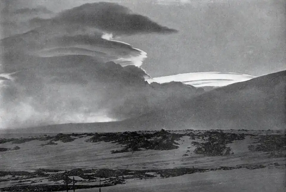 Photo of slightly curved clouds near the flank of a mountain